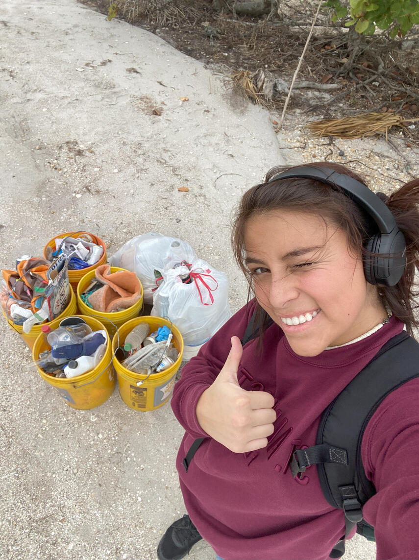 A volunteer poses with collected trash after another successful cleanup